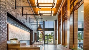 A modern reception area with a wooden reception desk, a large window offering a view of the outdoors, and a staircase leading to an upper level.