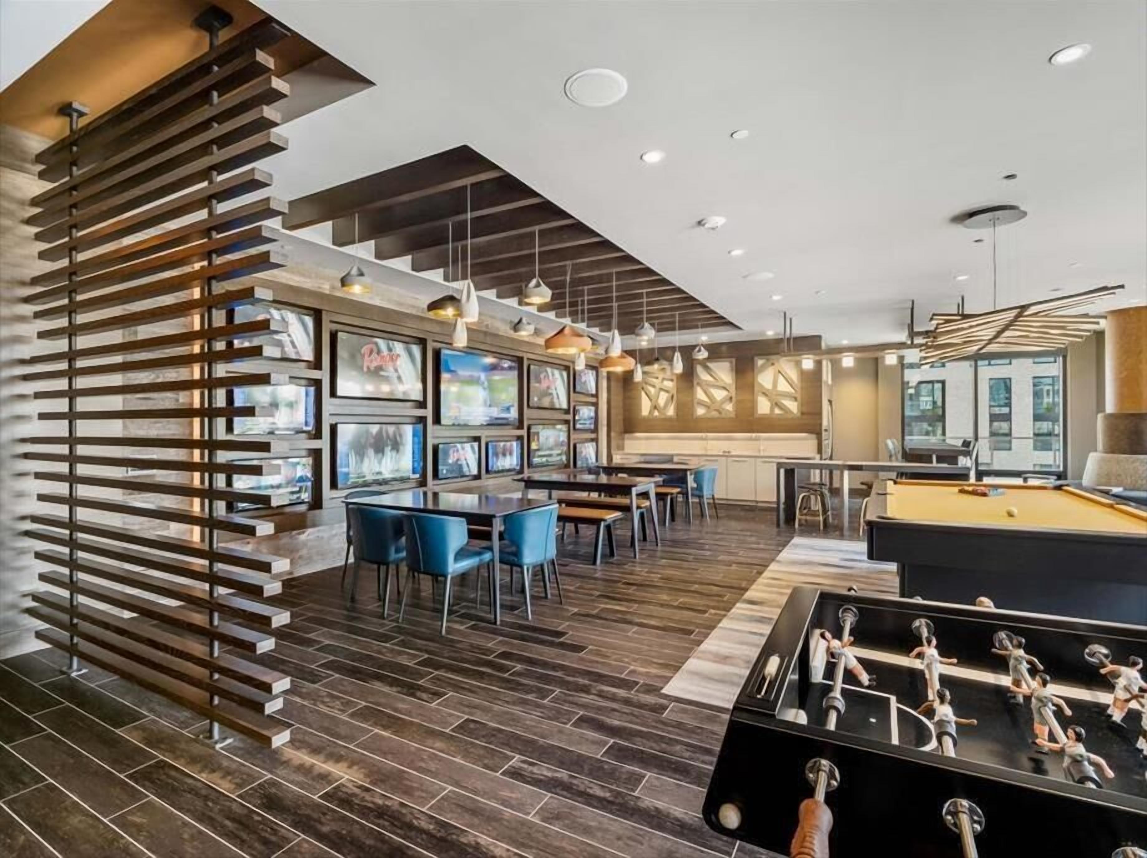 Un espace intérieur moderne comprenant une table de billard, des chaises bleues et une table de baby-foot.