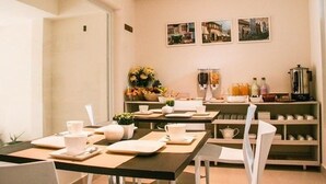 A dining area with tables set for breakfast, a fruit bowl, and a coffee machine. - Hotel Barrio 14 (Antofagasta)