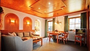 A cozy living room with a sofa, dining table, and chairs, wooden ceiling, and a television. - Apartment Westernberg 55sqm, terrace, kitchen, 1 bedroom, 1 bedsit. (Ruhpolding)