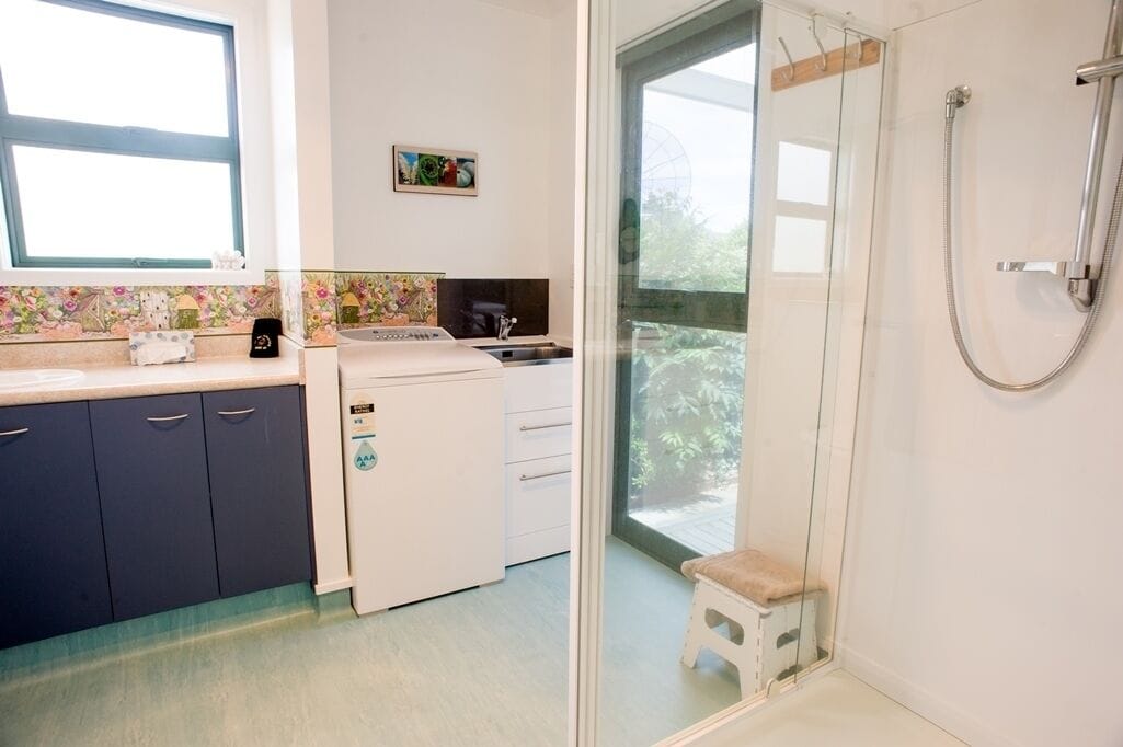 Un baño moderno con cabina de ducha de vidrio, un taburete pequeño y un lavamanos con grifo.