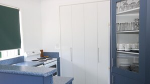 A kitchen with a stove, a sink, and a cabinet with glassware. - eMotel Napier (Napier)