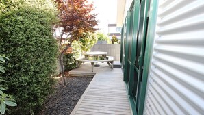 A wooden deck leading to a picnic table and a building with green shutters. - eMotel Napier (Napier)