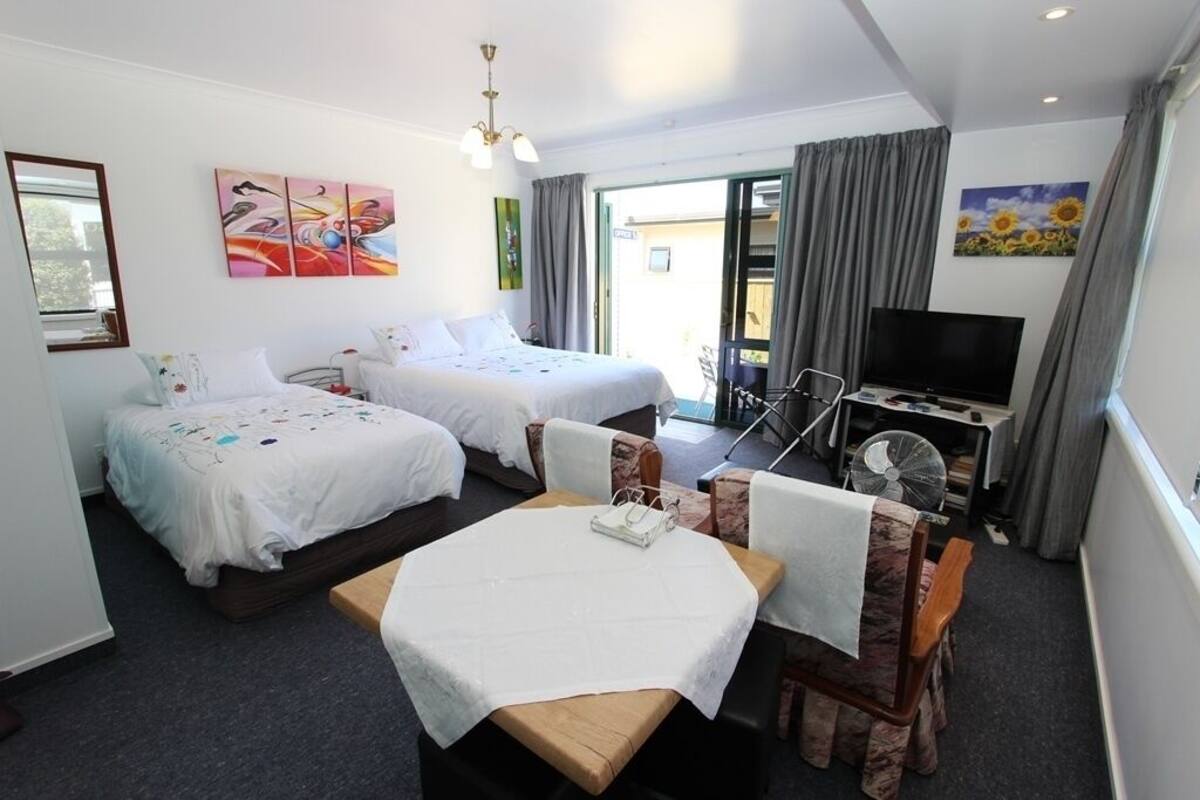 Una habitación de hotel con dos camas, televisión, mesa de comedor y una silla.