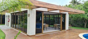 Et moderne hus med træterrasse, swimmingpool og terrassemøbler.