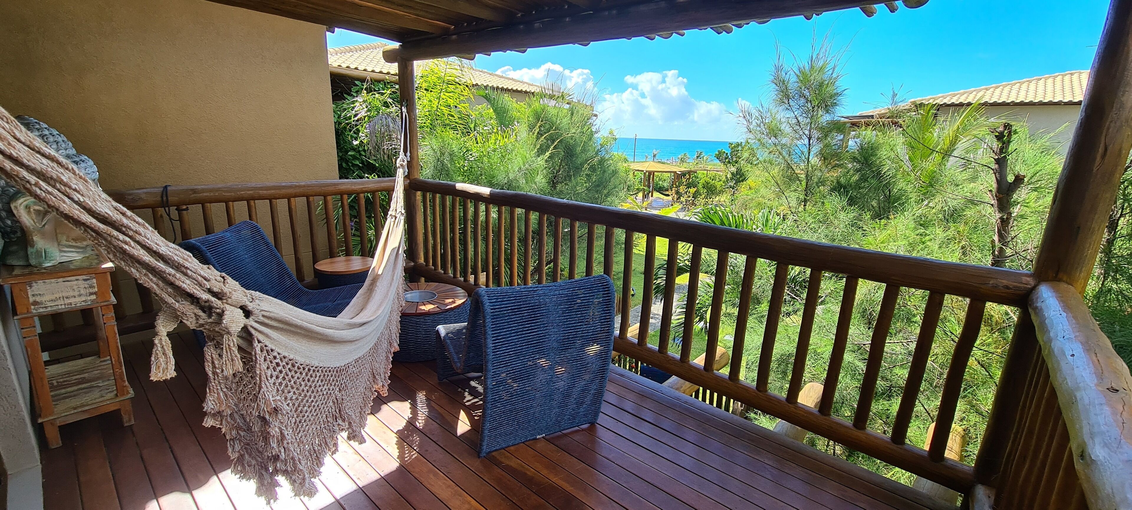 A wooden deck with a hammock, wicker chairs, and a small table.