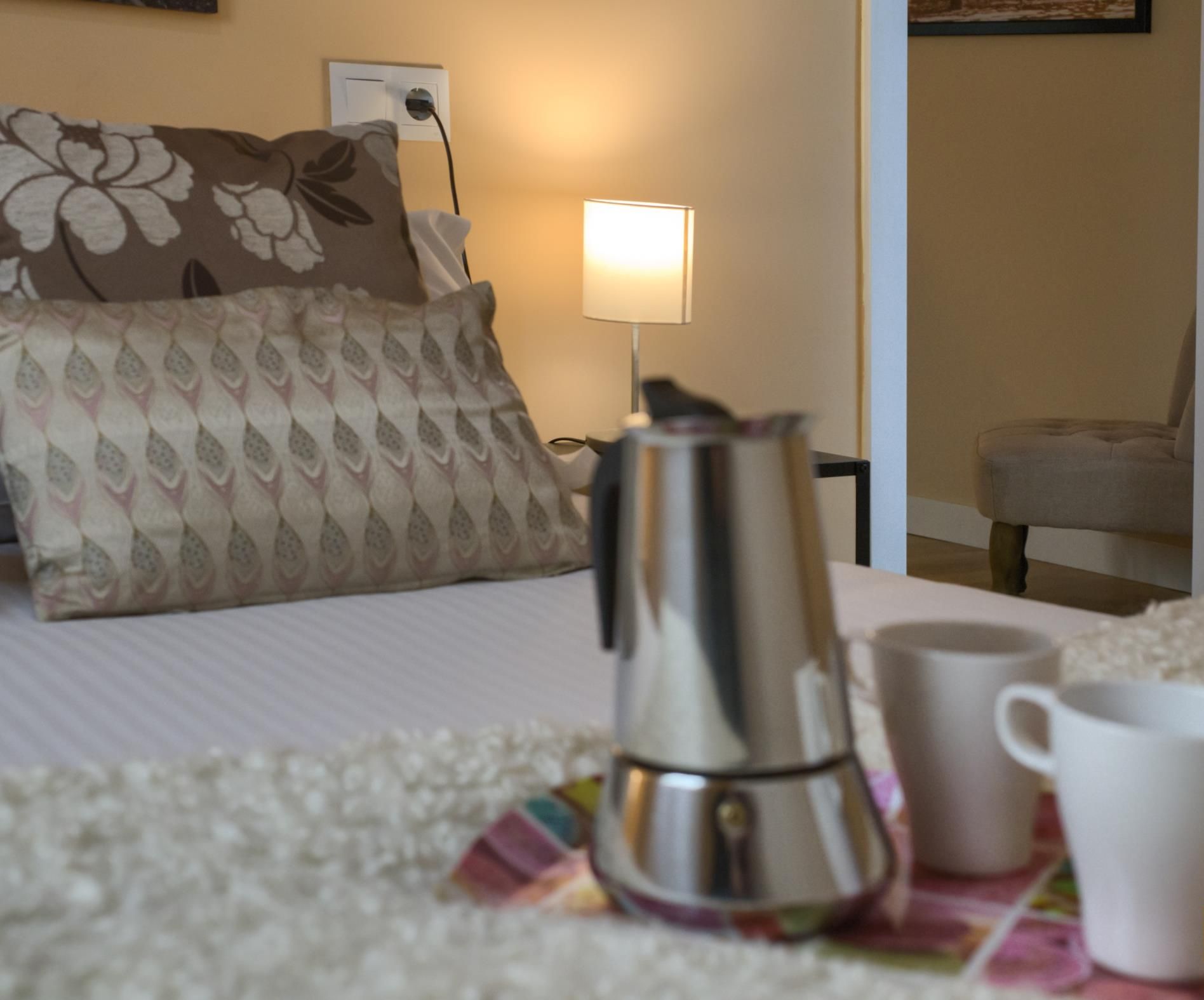 Una habitación de hotel con una cama, una cafetera y dos tazas sobre una mesa.
