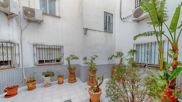 Un cortile con piante in vaso, pavimento piastrellato e condizionatori d'aria a parete.