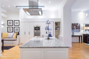 A modern kitchen with white cabinetry, a granite countertop, and stainless steel appliances. - Turn of the century elegance with a modern twist  II (V. kerület)