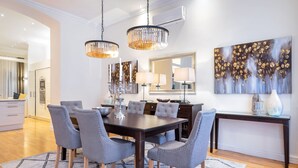 Un coin repas avec une table en bois foncé, des chaises à revêtement gris et un tapis à motifs.