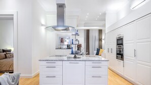 Une cuisine moderne avec des meubles blancs, un îlot central et des appareils électroménagers intégrés.