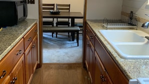 Una cucina con mobili in legno, un piano di lavoro in granito, un lavello e un'area pranzo con una panca e un tavolo.