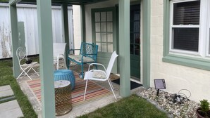 Un'area patio coperta con mobili da esterno, un piccolo tavolo e una pianta in vaso.