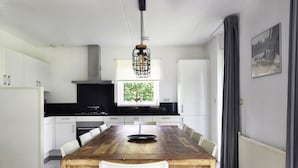 Una cocina moderna con armarios blancos, una mesa de comedor de madera y un lámpara colgante.