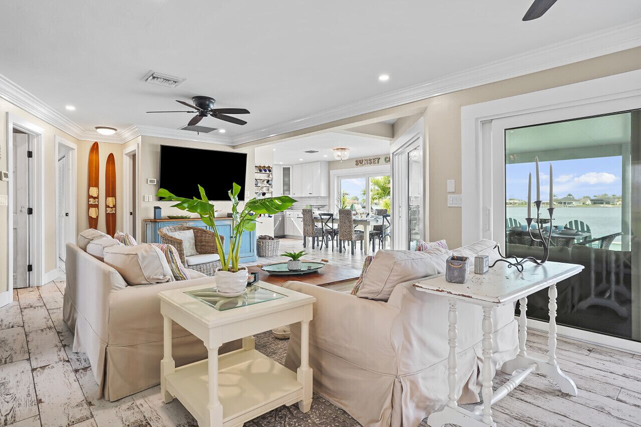 A spacious living area with a sofa, a coffee table, and a dining table. There is a view of the ocean through large windows.