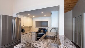 A modern kitchen with stainless steel appliances, white cabinetry, and granite countertops. - SPECTACULAR BALDY VIEW REMODELED 2 BD TOWNHOME NEXT TO LIFTS! LUXURY! LOCATION! (Ketchum)