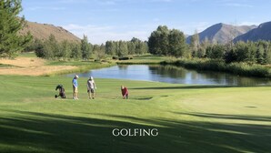 A golf course with a pond, trees, and mountains in the background. - SPECTACULAR BALDY VIEW REMODELED 2 BD TOWNHOME NEXT TO LIFTS! LUXURY! LOCATION! (Ketchum)