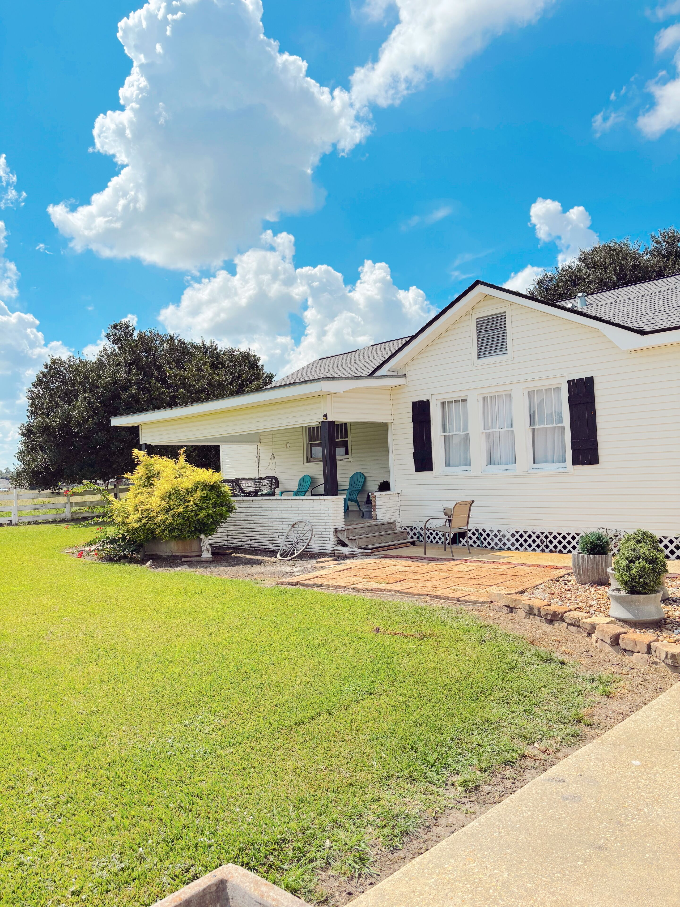 A single-story white house with a covered porch, a small front yard, and a clear blue sky.