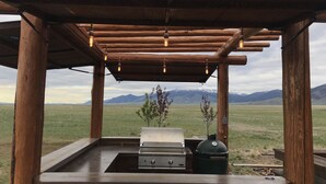 Uma área de churrasco ao ar livre com vista para montanhas ao fundo.