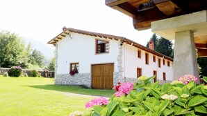 A white building with a stone base, a wooden door, and a window. - House with Garden and Barbecue in Llanes - Molinin (Ardisana)