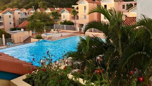 A resort with a swimming pool, palm trees, and a mountainous backdrop. - HamO Cosy: Sainte Anne apartment (Sainte Anne)