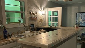 Une cuisine avec un îlot central, une horloge au mur et un ventilateur de plafond.