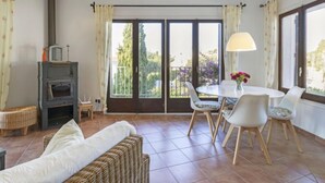 Una sala de estar con chimenea, una mesa de comedor con sillas, un sofá y vistas a través de puertas de cristal grandes.