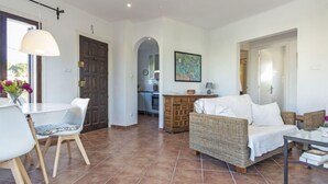 Amplia sala de estar con una mesa de comedor, sillas, un sofá y una cocina al fondo.