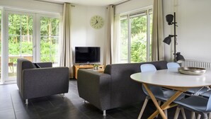 Een moderne woonkamer met een bank, een televisie, een eettafel en stoelen.