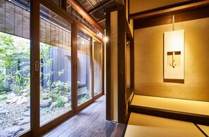 A traditional Japanese room with tatami flooring, sliding doors, and a small garden view. - Zen (Kyoto)
