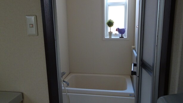 Een kleine badkamer met een bad, een raam en een kamerplant.