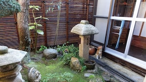 Een traditionele Japanse tuin met stenen lantaarns, een bamboebegraafsel en een vijver met koi karpers.