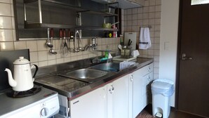 Een kleine keuken met een gasfornuis, twee spoelingen en roestvrijstalen apparatuur.