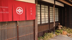 Een traditioneel Japans gebouw met een rode entreebanner met daarop 'WELCOME to ANA-TEI' en een houten constructie met schuifdeuren.