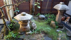 Een traditionele Japanse tuin met stenen lantaarns, een bamboeboomhek en een klein vijvertje.