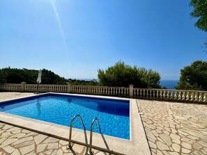 Ein rechteckiger Pool mit klarem, blauem Wasser, umgeben von einer Steindeck und einem Geländer.