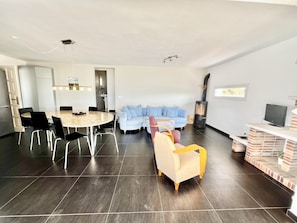 Ein modernes Wohnzimmer mit Essbereich, einer Sofagarnitur, einem Kamin und einem Fernseher.