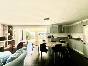 Eine moderne Küche mit Essbereich, integriertem Fernseher und Blick ins Freie.