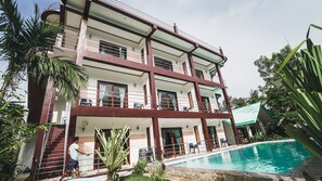 A multi-story hotel with a swimming pool, balconies, and outdoor seating. - Ocean 202 Home Stay (General Luna)
