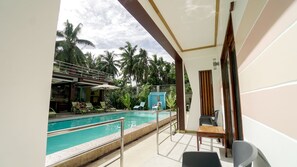 Zona de piscina con vista despejada, sillas de descanso y una pequeña mesa.