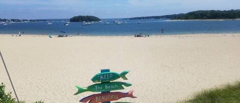 A beach with a signpost with multiple directional signs.