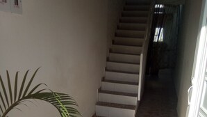 A narrow hallway with a stone floor, a staircase, and a door on the right. - Casa Love (Guadalajara de Buga)