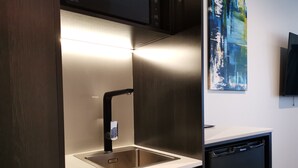 Une cuisine moderne dotée d’un évier en acier inoxydable, d’un robinet noir et d’un lave-vaisselle.