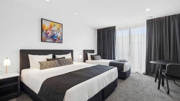 Une chambre d’hôtel avec deux lits, un bureau et une chaise.