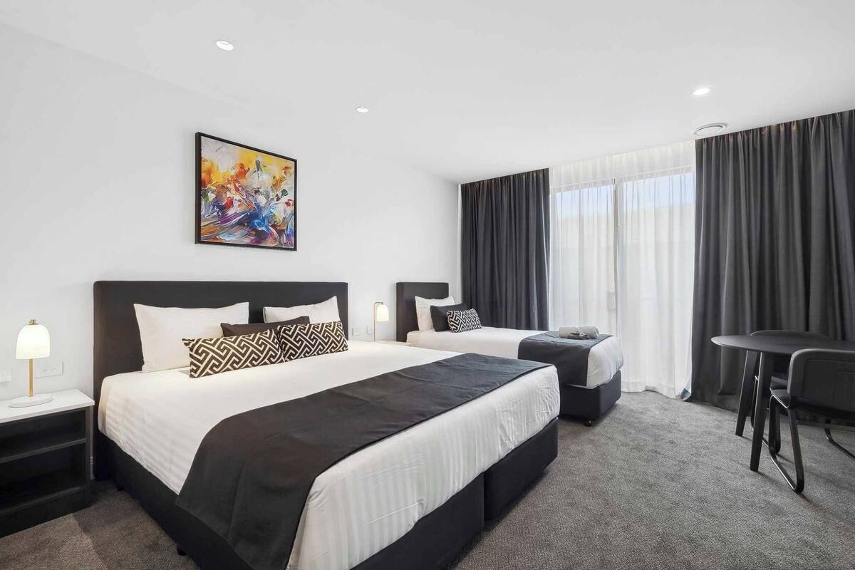 Habitación de hotel con dos camas, un escritorio y una silla.