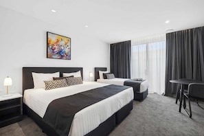 Une chambre d’hôtel avec deux lits, un bureau et une chaise.