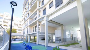 Un bâtiment moderne à plusieurs étages, doté d’un espace de jeux extérieur et d’une galerie couverte.