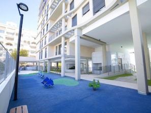 A multi-level building with a rooftop playground area featuring play equipment.