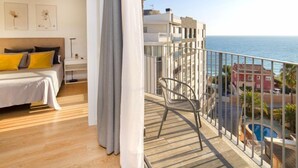 Un balcon avec vue sur la mer, un lit avec des coussins jaunes et une chaise.