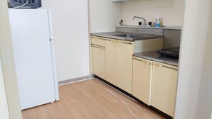 Una cocina compacta con fregadero, armarios y refrigerador.